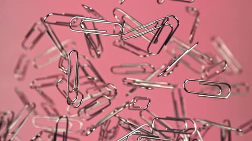Silver Paper Clips Floating on Pink Background
