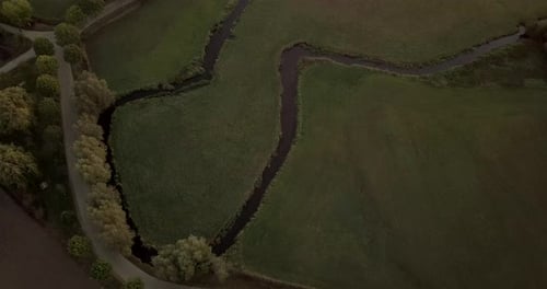 birds eye view of a little stream in a field during sunrise