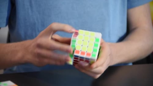 Ein Teenager löst einen 5x5 Zauberwürfel, Ende der Auflösung, Hände bewegen sich schnell