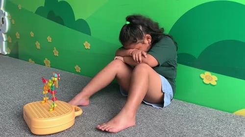 Sad depressed asian little girl siiting with her toys