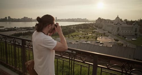 Man Taking Pictures of City Buildings at Sunset