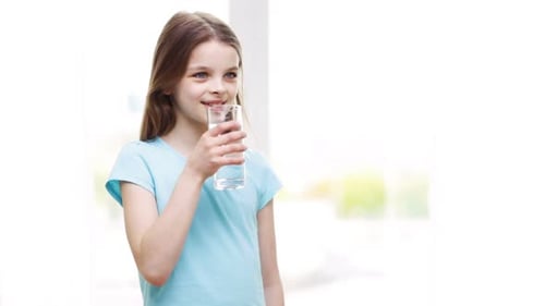 Young Girl Drinks Water in Bright Indoor Setting