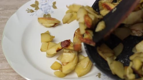 Cooked potatoes served into white plate with wooden spatula, close up