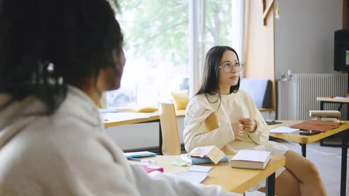 Dois estudantes multirraciais se envolveram em uma animada discussão enquanto estudavam em uma biblioteca moderna durante