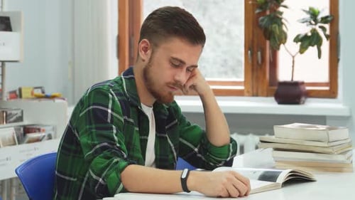 Tired Student Reading Book and Yawning