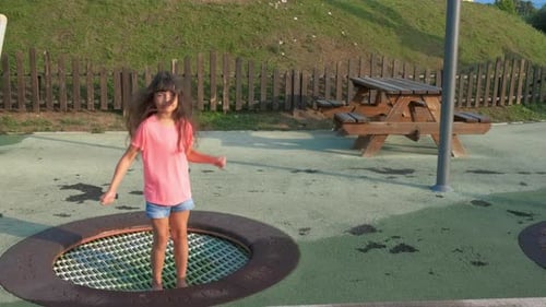 Girl Playing on Trampoline in Playground