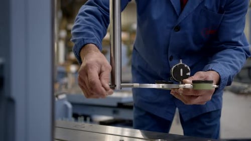 Blue dressed mechanic adjusting mechanical measuring instrument in slow motion