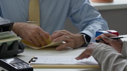 Female Client Signing Agreement while Getting Paper Cash from Bank Manager