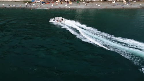 Drone Shot Of Tourists Riding In Speedboat Moving On Wavy Sea Near Beach