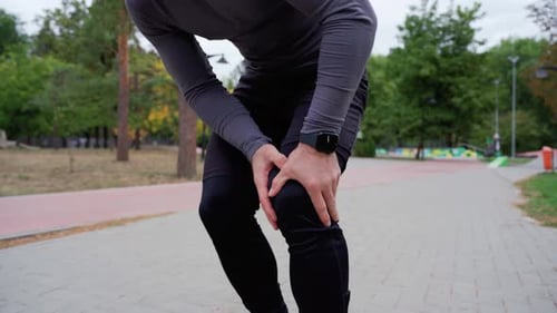 Man Having Painful Knee During Running Exercise Inside Park With Trees In Background Body Condition