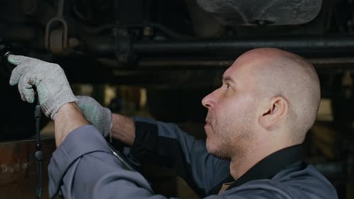 Middle-Aged Male Mechanic Servicing Truck in Auto Repair Shop