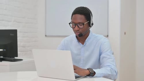 Young Adult Working at Computer with Headset