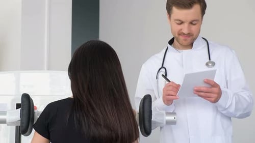 A Young Woman is Doing a Spinal Examination in a Diagnostic Machine with a Physiotherapist