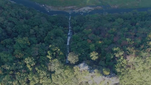 a thin-flowing waterfall in the mountains overlooking from above.