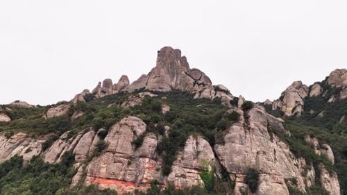 Prise de vue par drone avec une grue révélant gracieusement les sommets arrondis des falaises de Montserrat sur fond