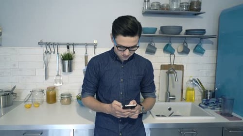 Man Using Phone in a Modern Kitchen