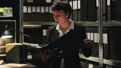 Woman Reviews Documents with Man in Dark Office