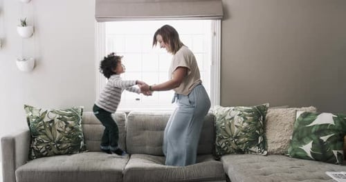 4k video footage of a little boy jumping on a sofa with his mother at home
