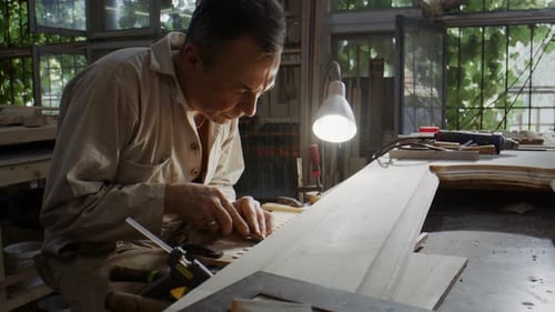 Focused Carpenter Carefully Shaping Wood in Workshop