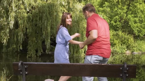 A Middleaged Caucasian Couple Dances with Smiles in a Park on a Sunny Day