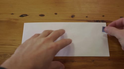 Close Up of a Man Putting a Stamp on a Blank Envelope