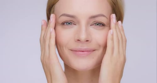 4k video footage of an attractive mature woman posing alone against a grey background in the studio