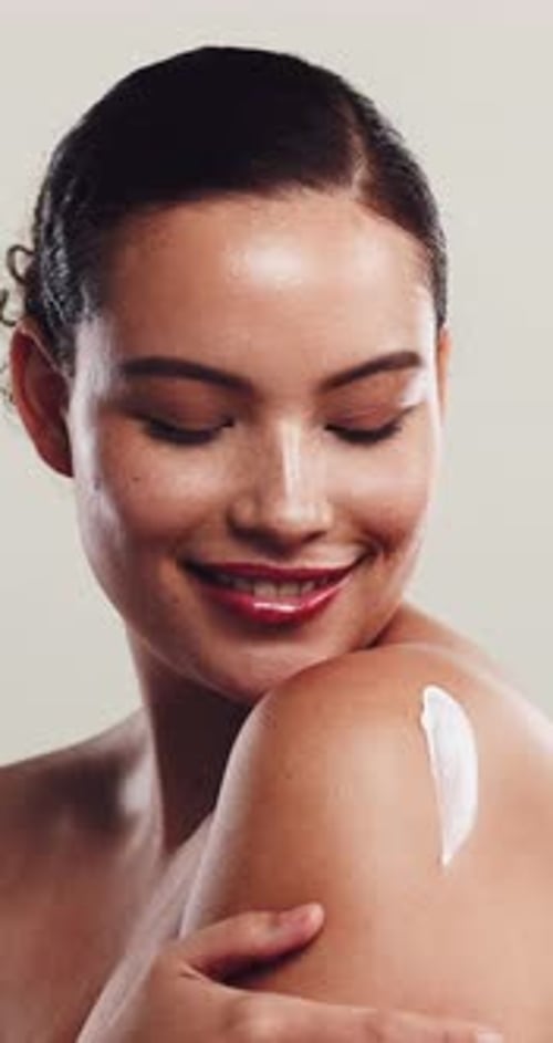 Smiling Woman Applies Cream To Her Shoulder