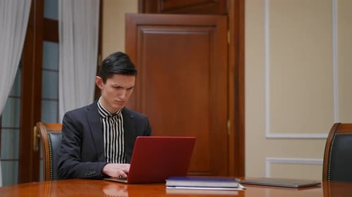 A Professional Man Working Diligently on His Laptop Within a Corporate Office Setting