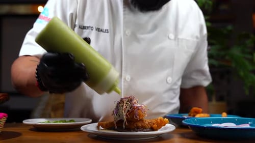 Chef putting sauce dressing avocado mousse guacamole mexican fish taco baja california style