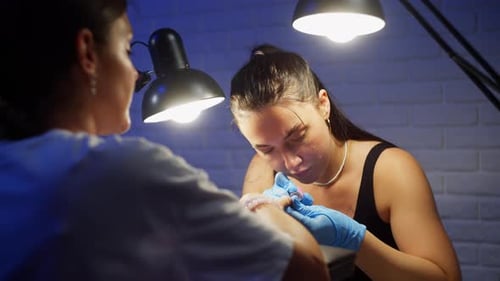 Woman Manicurist Applies Decorative Pearls to a Client's Nails