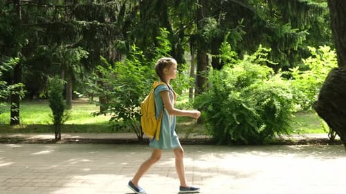 Ein Grundschüler geht morgens durch den Park zur Schule