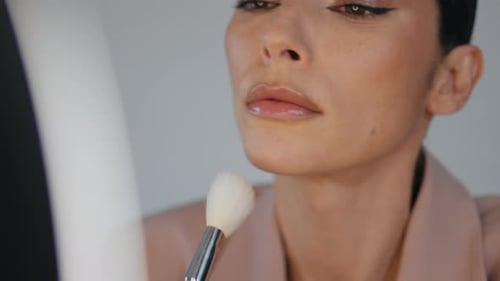 Elegant Woman Applies Makeup with a Brush