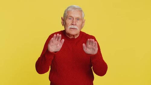 Senior Man Gesturing with Hands on Yellow Background