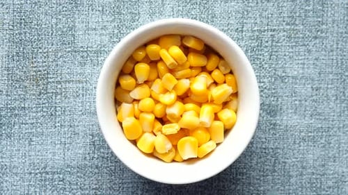Slow Motion of Sweet Corns Dropping in a Bowl on Table