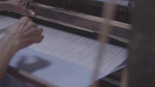 Eine Hand, die ein traditionelles Tuch auf einem Webstuhl bearbeitet