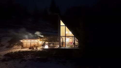Aerial View AFrame Cabin at Night A Glowing Aframe Cabin with Outdoor Amenities in a Snowy and