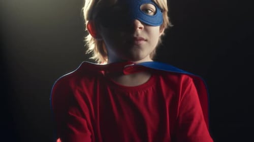 Little Superhero Posing on Dark Studio Background