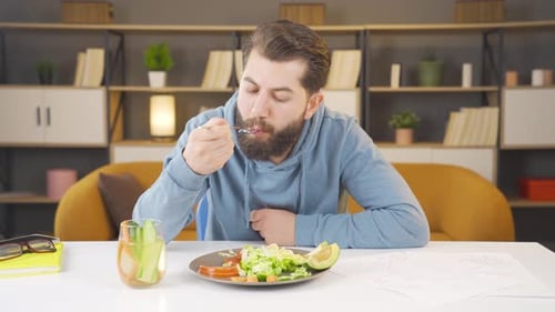 Bearded Man Eating a Salad at Home