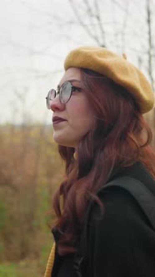 Side View of Lady with Red Hair Walking Through Autumn Forest Path