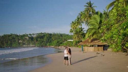 Young Biracial Happy Couple Unfocused Walking on the Beach Together Enjoying Summer Backview Shot