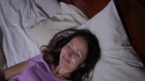 Dark-Haired Woman Smiling While Lying in Bed