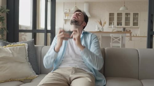 Man Playing Mobile Game on Couch at Home