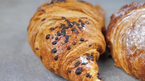 Dolly Shot Close Up of Two Delicious Croissants with Powdered Sugar and Chocolate