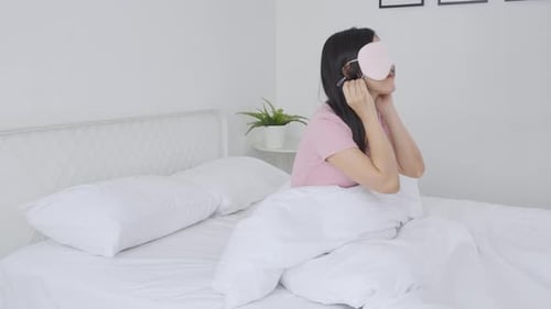 Beautiful young asian woman wearing cover eye and sleeping on bed with head on pillow comfort.