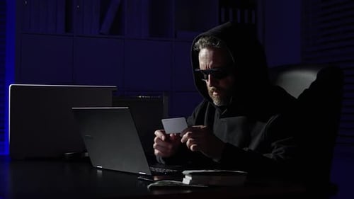 Man in Hood Working on Laptop at Desk