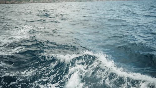 Blaues Meerwasser und Schaum auf den vom Schiff erzeugten Wellen, Nahaufnahme, in Zeitlupe.