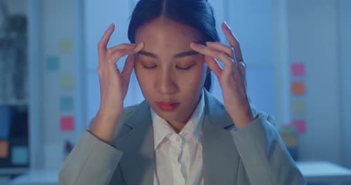 businesswoman rubbing eye feel pain and tired from overwork in office at night.