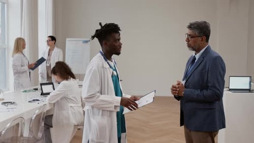 Doctor and Businessman Discussing Charts in Modern Office