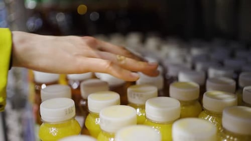 Hand Selects Orange Juice Bottle in Grocery Store