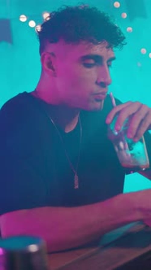 A Man is Savoring a Drink in a Trendy and Lively Bar Atmosphere Filled with Excitement and Energy